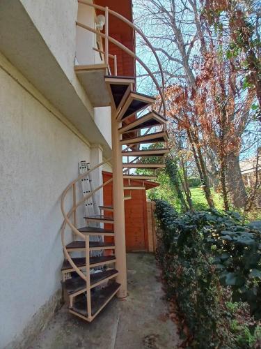 a wooden spiral staircase on the side of a building at Lent a Parton Apartmanház in Balatonudvari