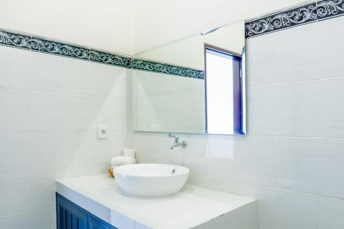 a white bathroom with a sink and a mirror at Lebak Agung Guest House in Canggu