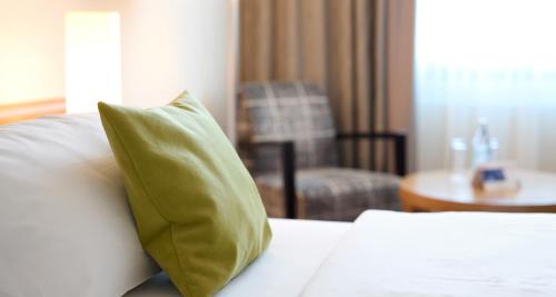 a green pillow on a bed in a hotel room at Best Western Plus Arosa Hotel in Paderborn