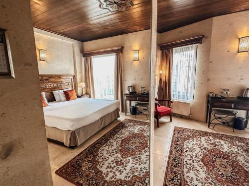 a bedroom with a bed and a desk and windows at Osmanli Cappadocia Hotel in Goreme