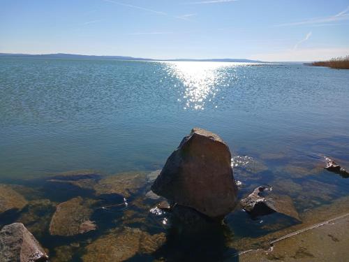 a large rock in the middle of a large body of water at Lent a Parton Apartmanház in Balatonudvari