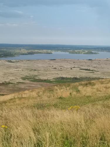 a view of a field with a lake in the distance at Le Roc'h Mousse Gîte de Charme en Centre Finistère in Plonévez-du-Faou