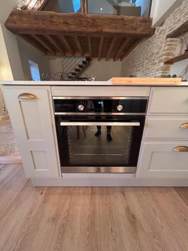 a kitchen with a oven in a white kitchen at Au 8 à Meursault, Magnifique maison Bourguignonne au pied des vignes, jardin, places de parking privée in Meursault