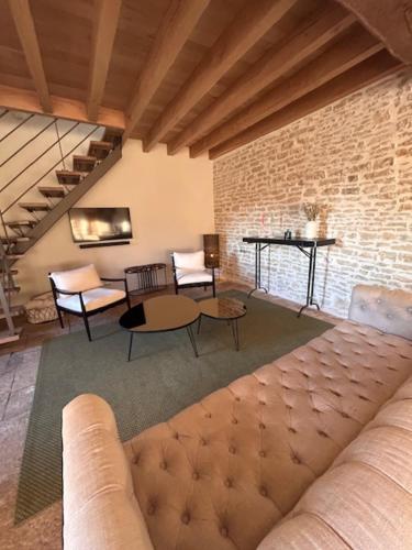 a living room with a couch and chairs and a brick wall at Au 8 à Meursault, Magnifique maison Bourguignonne au pied des vignes, jardin, places de parking privée in Meursault