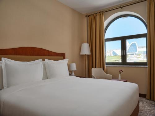 a bed in a hotel room with a large window at The Central Point Hotel Baku in Baku
