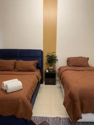 a bedroom with two beds and a plant on the floor at Orked Homestay Bagan Serai in Bagan Serai