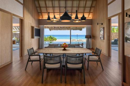 a dining room with a table and chairs and the ocean at JW Marriott Maldives Kaafu Atoll Island Resort in Male City