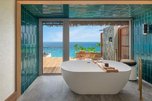 a bath tub in a bathroom with a view of the ocean at JW Marriott Maldives Kaafu Atoll Island Resort in Male City