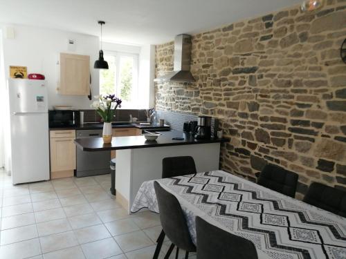 une cuisine avec une table et un mur en briques dans l'établissement Maison Jullouville au calme, à Jullouville
