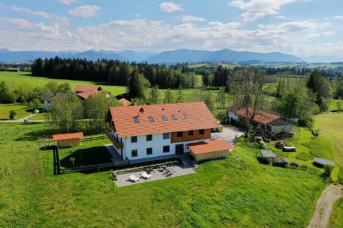 a house with a red roof on a green field at Beautiful new building attic apartment Viktoria in Böbing