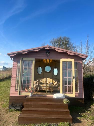 ein kleines rosa winziges Haus mit einer Veranda in der Unterkunft The Pink Cottage upstairs suite & Garden Summer Room in Whitehead