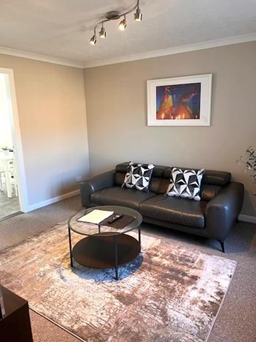 a living room with a leather couch and a table at Kelpies Serviced Apartments Hamilton- 2 Bedrooms in Falkirk