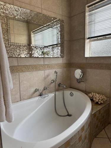 a white tub in a bathroom with a mirror at Ben & Bern House in Krugersdorp