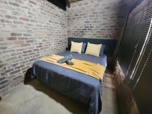a bed in a room with a brick wall at Lazy River Retreat in Pretoria
