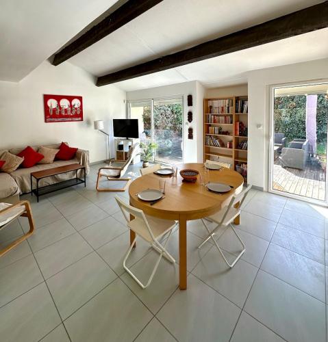 un salon avec une table et des chaises en bois dans l'établissement La Family House - Calme & Spacieuse, 20mn Plages & Montpellier, à Vendargues