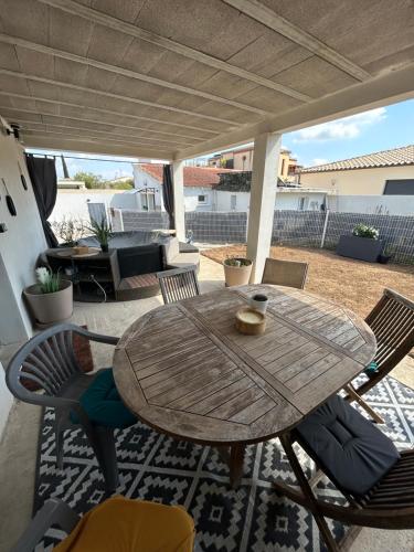 une table et des chaises en bois sur une terrasse dans l'établissement Villa LUNEL, à Lunel