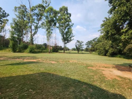 a large grass field with trees in the background at Lazy River Retreat in Pretoria