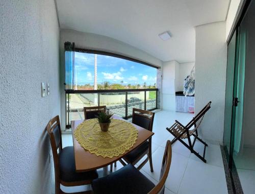 a dining room with a table and chairs and a large window at Varanda Gourmet Diversão Pet Praia do Francês in Praia do Frances