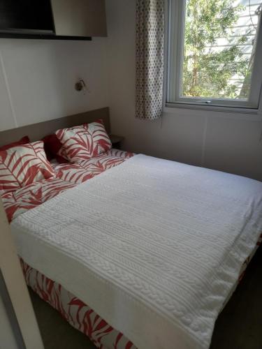 un lit dans une chambre avec une fenêtre dans l'établissement MOBIL HOME le BALARUCOIS, à Valras-Plage