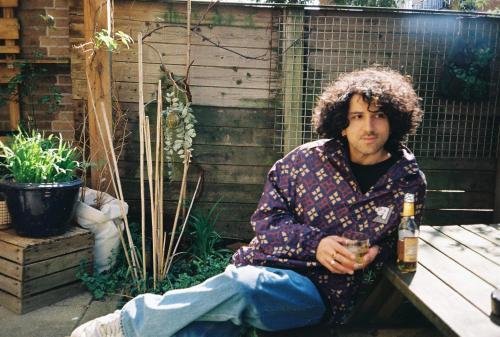 a man sitting on a bench with a bottle of beer at Hostel Ani&Haakien in Rotterdam