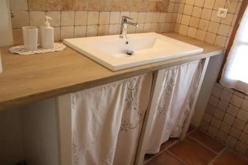 La salle de bains est pourvue d'un lavabo et de rideaux. dans l'établissement Gîte une treille en provence, à Saint-Didier