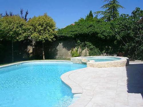 une piscine avec de l'eau bleue dans une cour dans l'établissement Gîte une treille en provence, à Saint-Didier