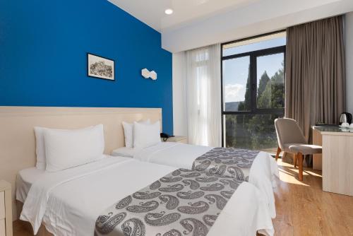 a hotel room with two beds and a blue wall at Iveria Inn Hotel in Tbilisi City