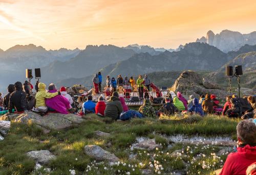 a crowd of people sitting on a hill watching a movie at Hotel Diamant Park in Campitello di Fassa