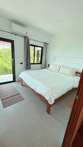 a large bed in a white room with a window at Koh Tao Studios Family Suite in Ko Tao