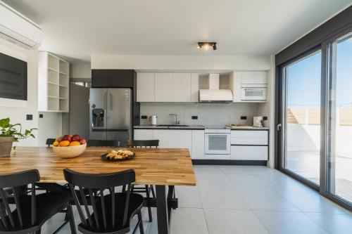 a kitchen with a wooden table and black chairs at Nos Aqua Villas Chania in Pazinos