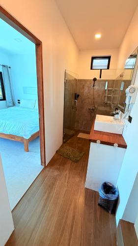 a bathroom with a shower and a sink and a bed at Koh Tao Studios Family Suite in Ko Tao