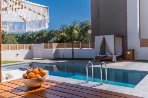 a bowl of fruit sitting on a table next to a pool at Nos Aqua Villas Chania in Pazinos