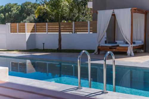 a swimming pool with two metal rails next to a house at Nos Aqua Villas Chania in Pazinos