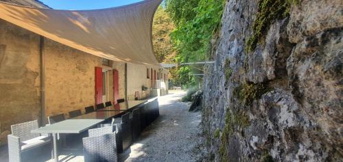 un bâtiment avec un mur en pierre, une table et des bancs dans l'établissement Le Bois Des Fées, à Les Martys