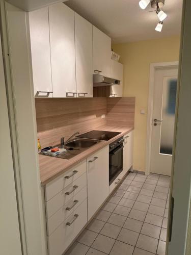 a kitchen with white cabinets and a sink at Weinmanns Wildgatter in Grafenwiesen