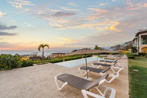 a row of lounge chairs sitting next to a pool at Infinity Pools & Sunsets Over Tamarindo Bay in Tamarindo