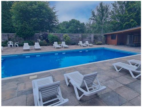 a swimming pool with chaises and chairs next to at Torwood 6 in Cenarth