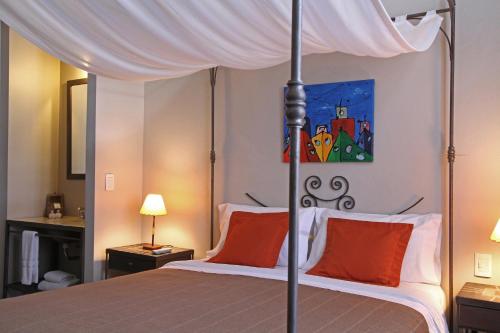 a bedroom with a canopy bed with orange pillows at A Hotel in Buenos Aires