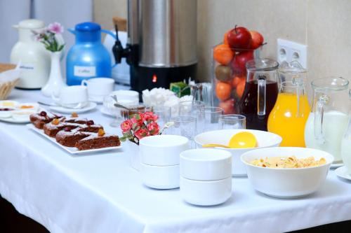 una mesa blanca con comida, bebidas y fruta en Soluxe Hotel, en Bishkek
