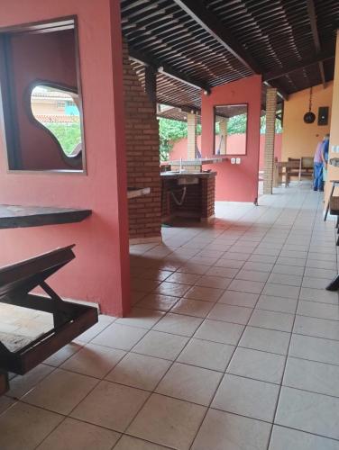 a building with red walls and a tile floor and benches at Casa d Amar in Paripueira