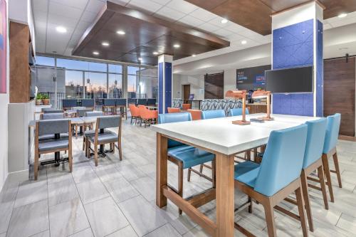 a dining room with tables and blue chairs at Holiday Inn Express & Suites Moore by IHG in Moore