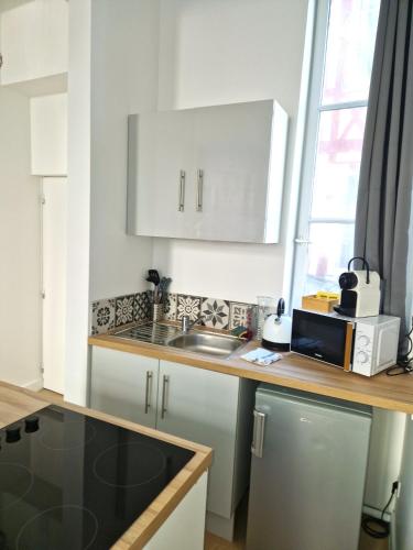 une cuisine avec des armoires blanches et un comptoir dans l'établissement Les Bons Enfants 6, à Rouen