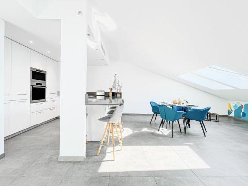 - une cuisine blanche avec des chaises bleues et une table dans l'établissement Sky Croisette - Palais des Festivals et des Congrès, à Cannes