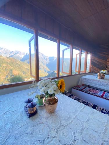 a room with a table with flowers and windows at Hill Garden Homestay in Uttarey