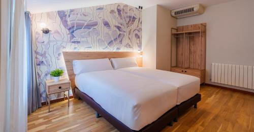 a bedroom with a white bed and a painting on the wall at Spirit Hotel Ciudad de Burgos in Rubena