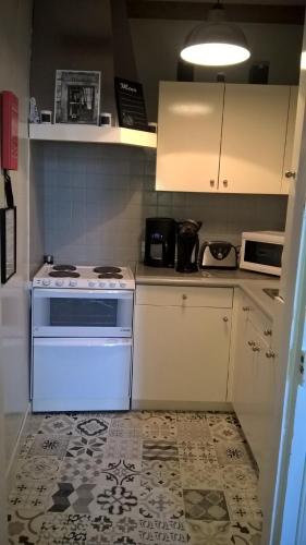 Il comprend une petite cuisine équipée d'un four avec plaques de cuisson blanches. dans l'établissement Charmant 2 pièces, hyper-centre, Avenue de la Mer, à Cabourg