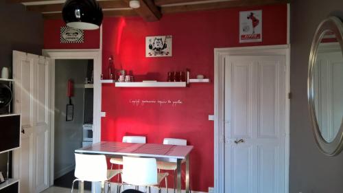 un mur rouge dans une cuisine avec une table et des chaises dans l'établissement Charmant 2 pièces, hyper-centre, Avenue de la Mer, à Cabourg