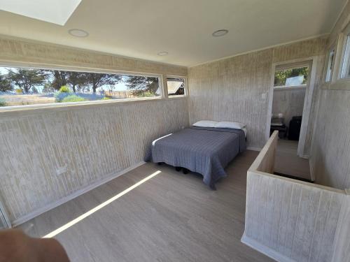 ein Schlafzimmer mit einem Bett in einem Zimmer mit zwei Fenstern in der Unterkunft Koru Ecolodge in Cáhuil