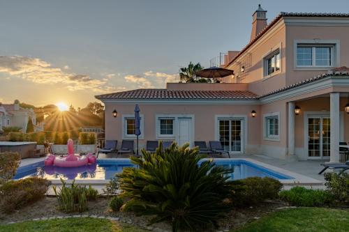 a villa with a swimming pool and a house at Extraordinary Villa on an elevated position in Quinta do Lago in Quinta do Lago