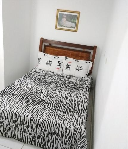 a bed with black and white sheets and pillows at Teresopolis Apartamento Proximo a Feirinha in Teresópolis